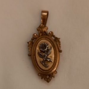 Pendentif Médaillon formant un petit boitier pour glisser un précieux souvenir Métal doré, décor de fleur